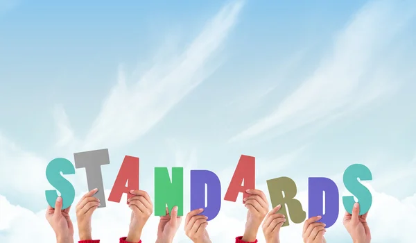 Composite image of hands holding up standards — Stock Photo, Image