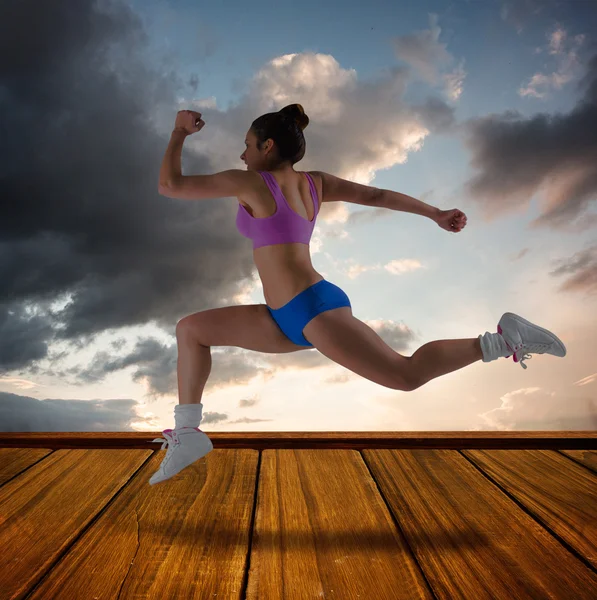 Imagen compuesta de morena en forma corriendo y saltando — Foto de Stock