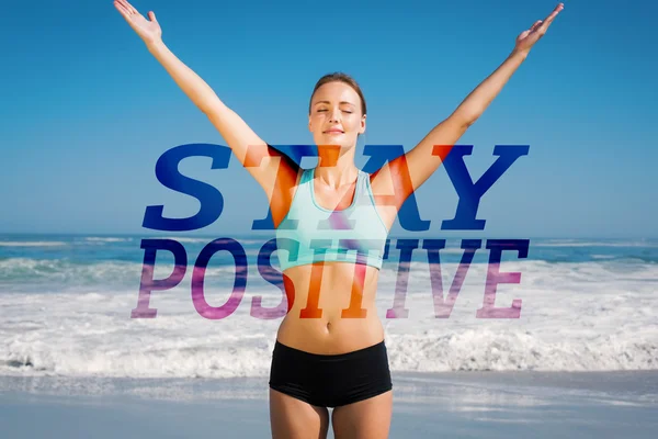 Fit woman standing on the beach with arms up — Stock Photo, Image