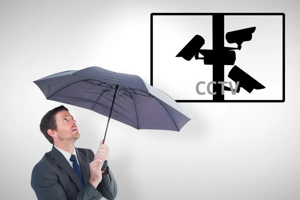 Empresário abrigando sob guarda-chuva preto — Fotografia de Stock