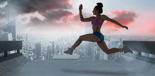 Composite image of fit brunette running and jumping — Stock Photo, Image