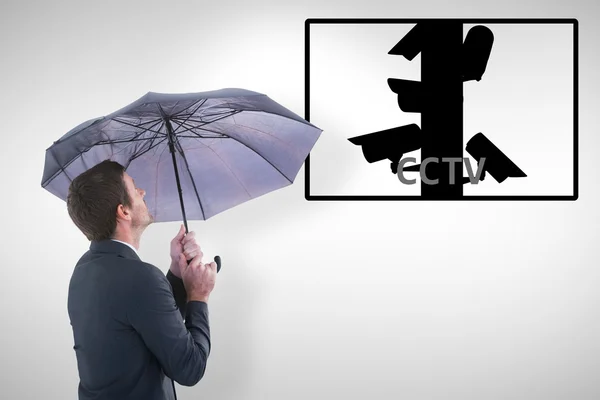 Geschäftsmann hält Regenschirm in der Hand, während er nach oben schaut — Stockfoto