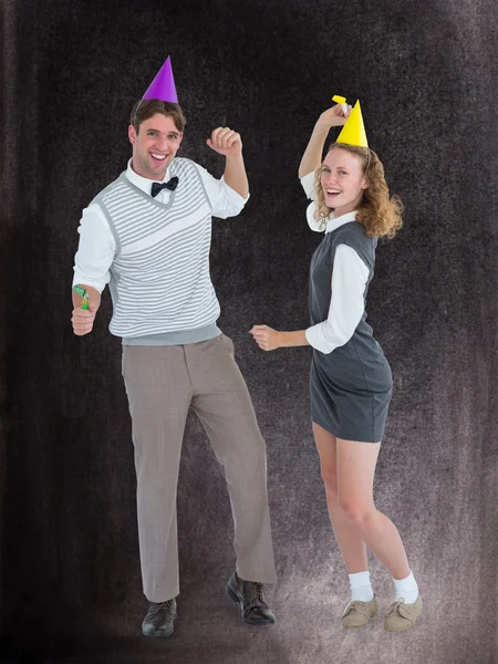 Composite image of geeky couple dancing with party hat — Stock Photo, Image