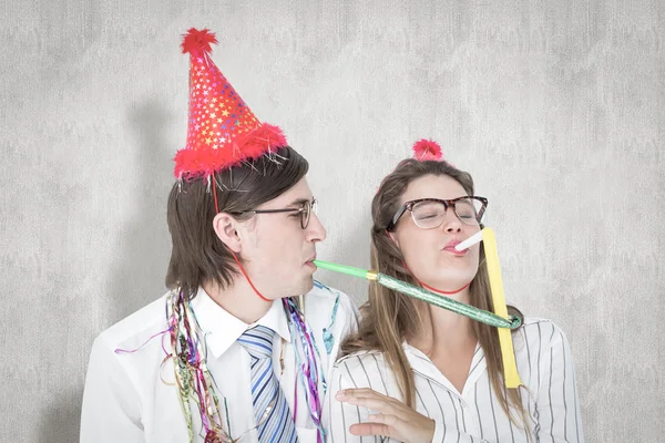 Geeky hipster wearing a party hat with blowing — Stock Photo, Image