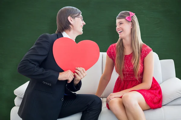 Composite image of cute geeky couple with red heart shape Stock Image