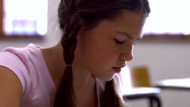 Schoolgirl reading at desk in school — Stock Video