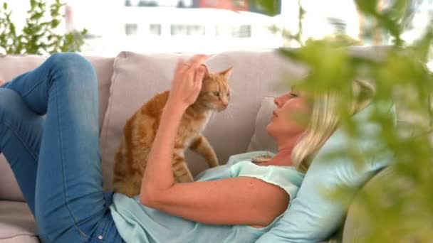 Loira feliz com gato de estimação no sofá — Vídeo de Stock