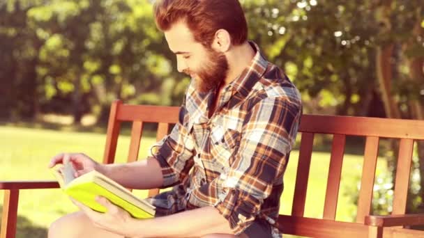 Knappe hipster boy lezen in het park — Stockvideo