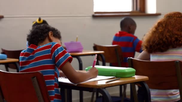 Niños de la escuela escribiendo en el aula — Vídeo de stock