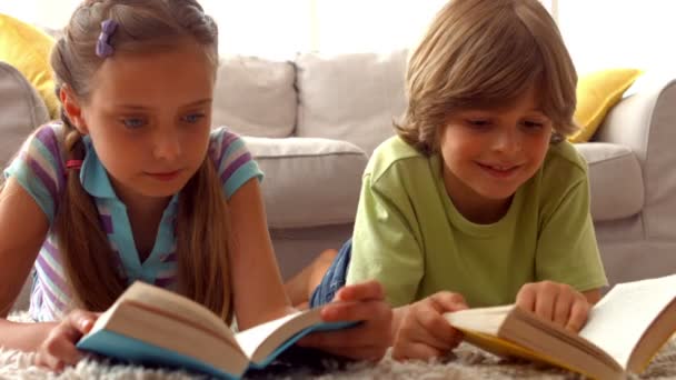 Братья и сёстры читают книги на полу — стоковое видео