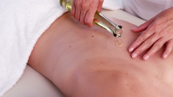 Masseurin gießt Öl für Massage — Stockvideo
