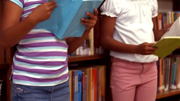 Lindos alumnos leyendo en la biblioteca — Vídeo de stock