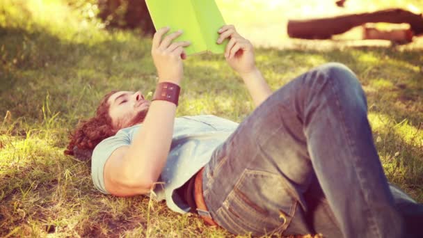 Joven leyendo libro en el parque — Vídeos de Stock