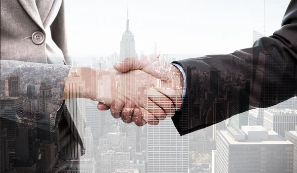 Businesspeople shaking their hands against city skyline — Stock Photo, Image