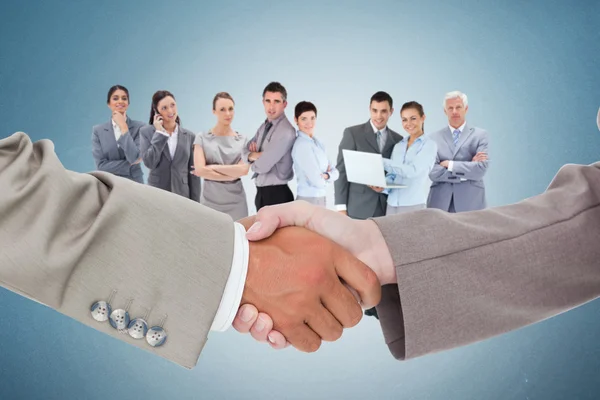 Shaking hands against business team — Stock Photo, Image