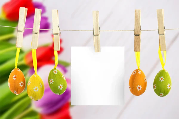 Hanging easter eggs against tulips on table — Stock Photo, Image