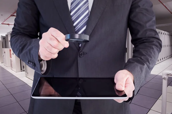 Kompositbild eines Geschäftsmannes, der Tablet mit Lupe betrachtet — Stockfoto