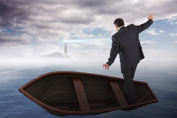 Businessman balancing in boat against calm sea — Stock Photo, Image