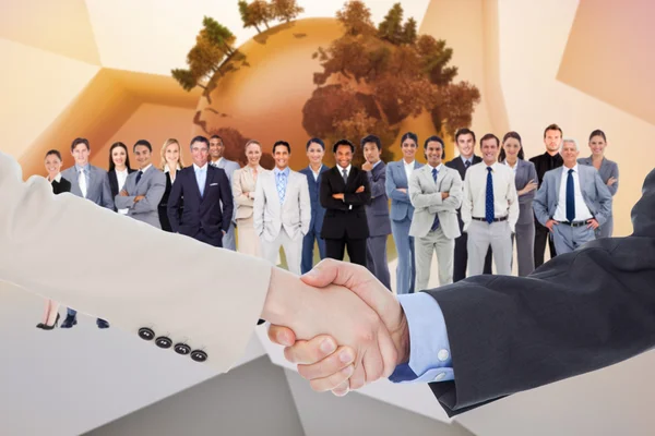 Composite image of smiling business people shaking hands while l — Stock Photo, Image