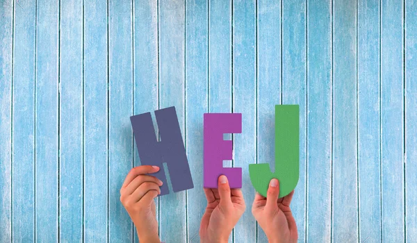 Hands holding up hej against wooden planks — Stock Photo, Image