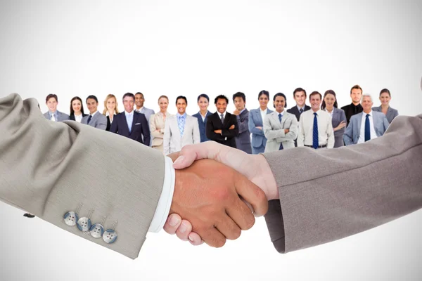 Shaking hands against business team — Stock Photo, Image