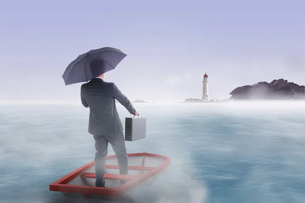 Podnikatel v lodi s deštníkem proti klidné moře — Stock fotografie