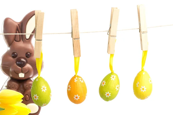 Hanging easter eggs against chocolate bunny — Stock Photo, Image