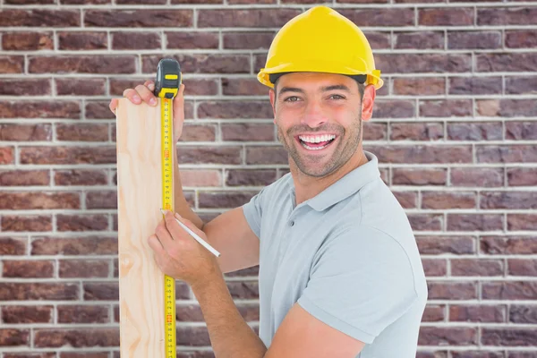 Worker using measure tape to mark on plank — Stock Photo, Image