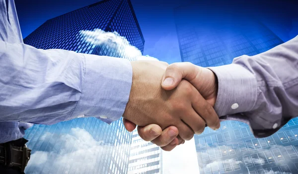Two men shaking hands against skyscrapers — Stock Photo, Image