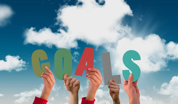Hands holding up goals against blue sky — Stock Photo, Image