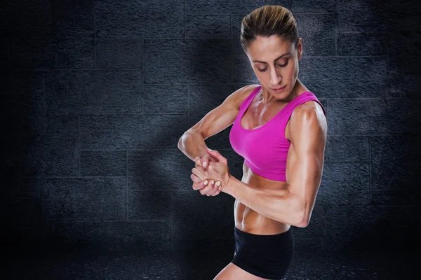 Composite image of female bodybuilder flexing in pink sports bra — Stock Photo, Image