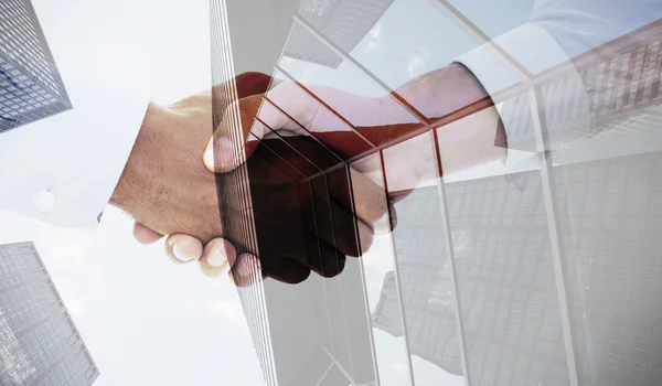 Handshake in office against skyscraper — Stock Photo, Image