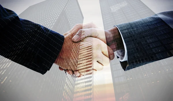 Business people shaking hands against skyscrapers — Stock Photo, Image