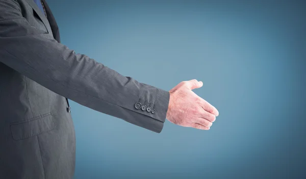 Businessman holding his hand out against blue — Stock Photo, Image