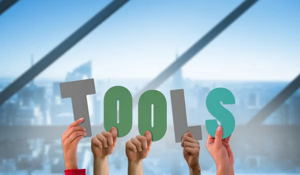 Hands holding up tools against room — Stock Photo, Image