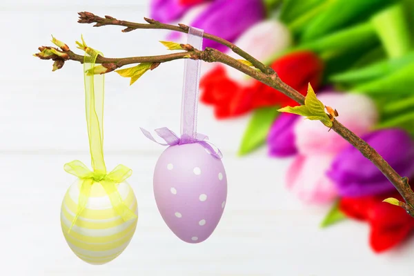 Hanging easter eggs against tulips — Stock Photo, Image