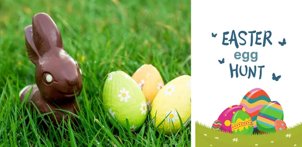 Chocolate bunny in the grass with easter eggs — Stock Photo, Image