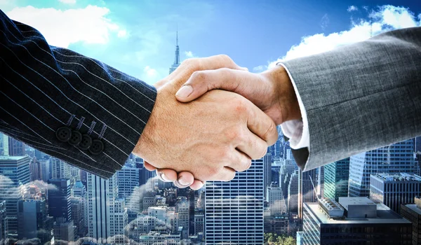 Business people shaking hands against skyline — Stock Photo, Image
