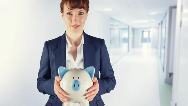 Composite image of businesswoman showing piggy bank — Stock Photo, Image