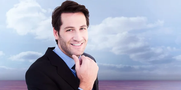 Composite image of businessman touching his chin while smiling a — Stock Photo, Image