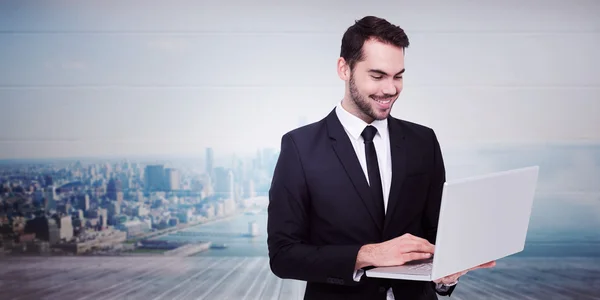 Uomo d'affari sorridente in piedi e utilizzando laptop — Foto Stock