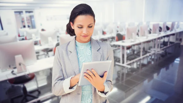 Composite image of brunette using tablet pc — Stock Photo, Image