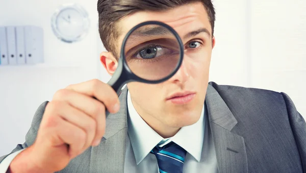 Businessman looking through magnifying glass — Stock Photo, Image