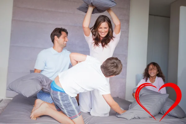 Familia teniendo una pelea de almohadas en la cama —  Fotos de Stock