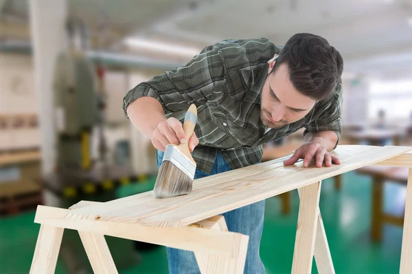 Worker using brush on wooden plank — Stock Photo, Image