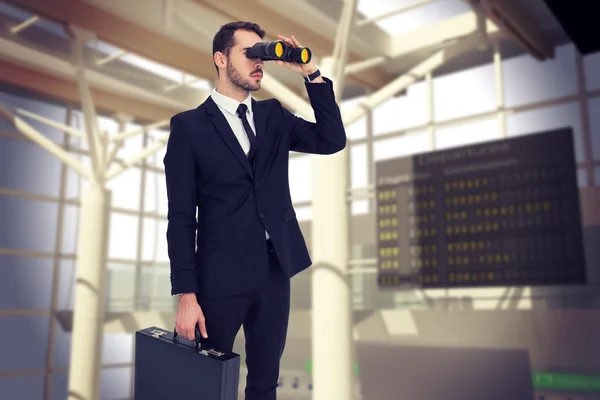Empresario sosteniendo maletín mientras usa binoculares —  Fotos de Stock