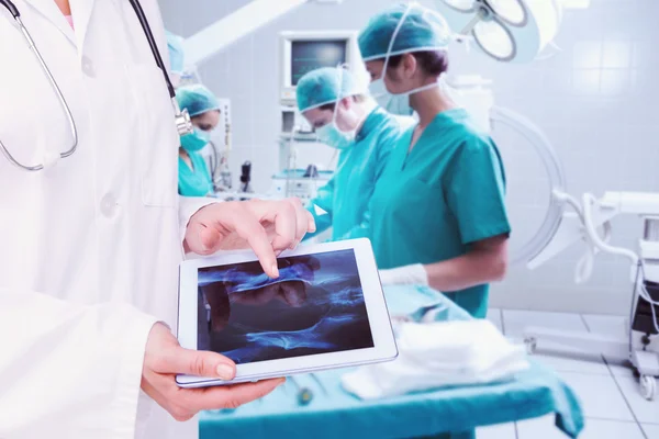 Композитне зображення лікаря, який дивиться на рентген на планшеті — стокове фото