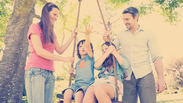 Szczęśliwa para pchanie dzieci na swing — Zdjęcie stockowe