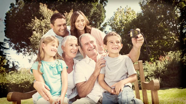 Família sentada em um banco tirando fotos de si mesmos — Fotografia de Stock