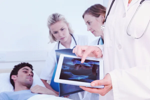 Composite image of doctor looking at xray on tablet — Stock Photo, Image